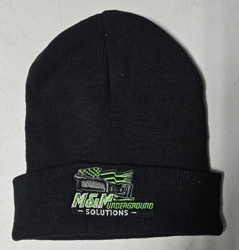 Black cuffed beanie with the green and white M&M Underground Solutions logo embroidered on the cuff