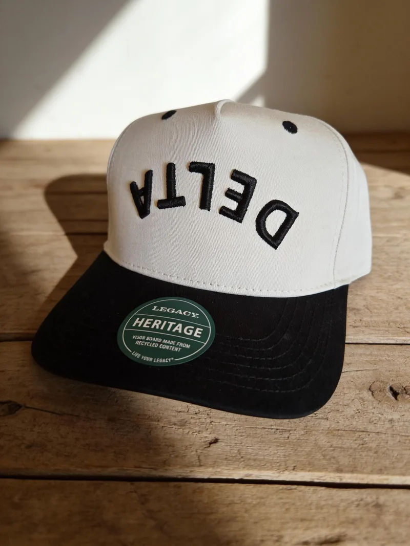 Cream and black cap with DELTA embroidered in black letters