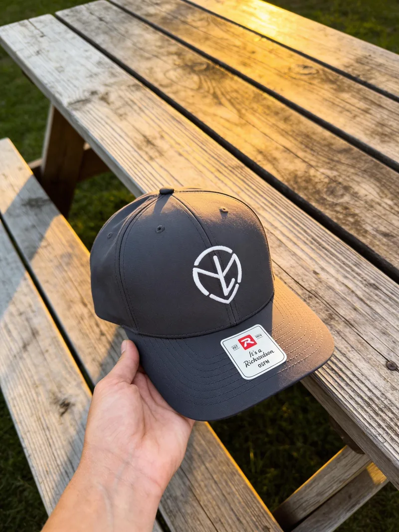 Charcoal cap with a round monogram logo embroidered in white thread