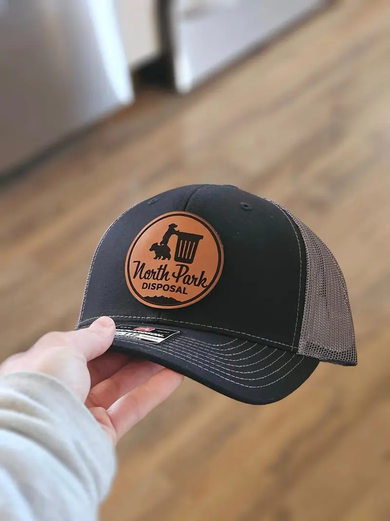 Black trucker hat with a round leather North Park Disposal patch